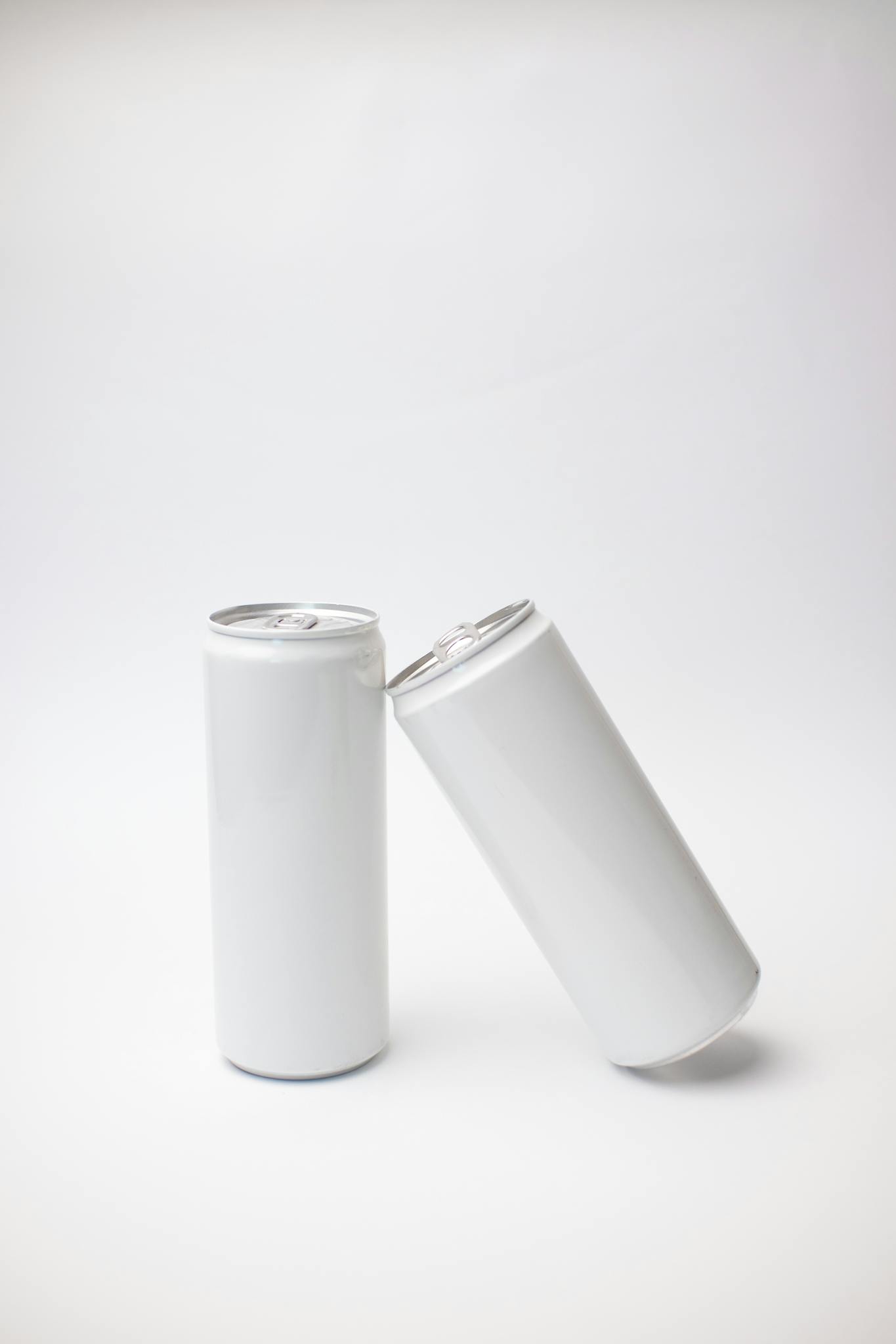 Minimal mockup of two white soda cans against a plain background, ideal for product display.