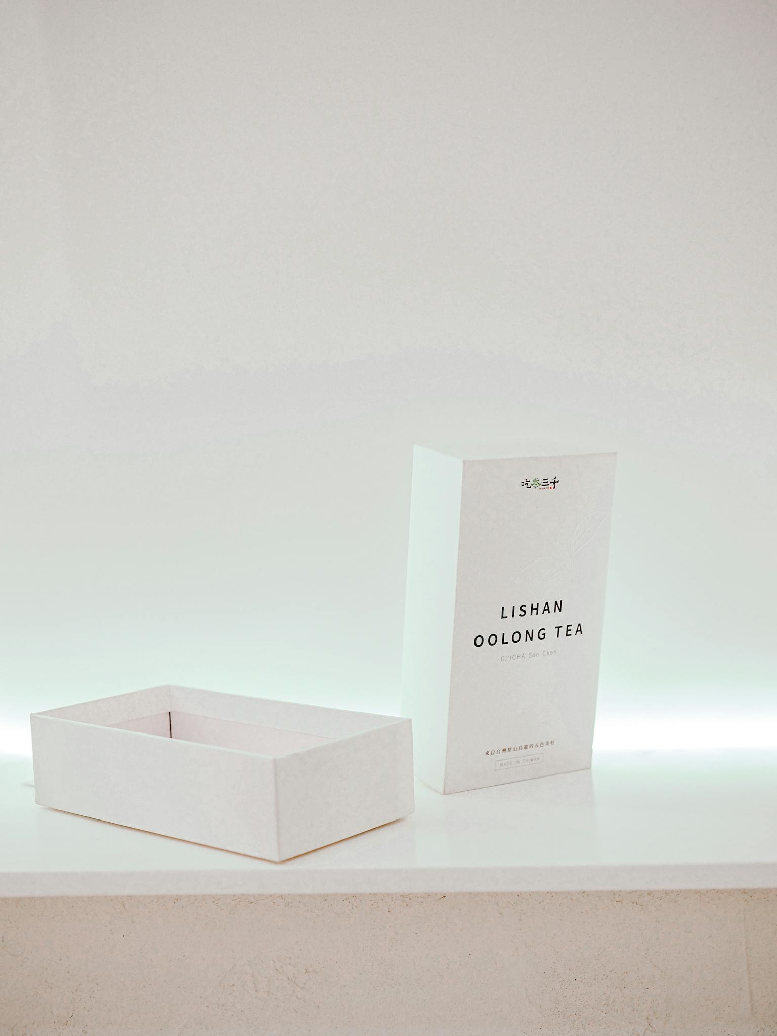 Minimalist white packaging for Lishan Oolong Tea with box and light background.