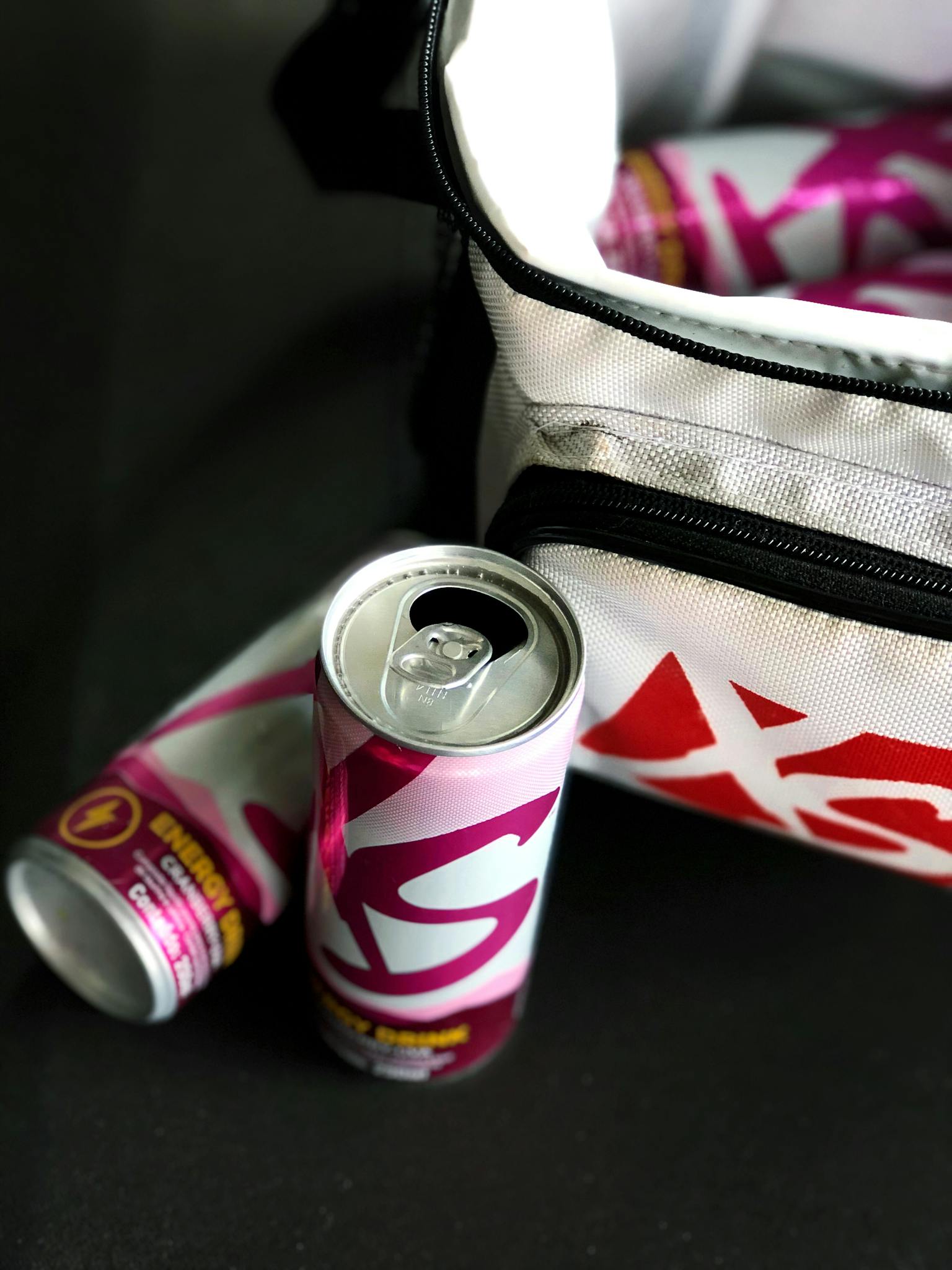 Vibrant energy drink cans positioned near a cooler bag, showcasing product details in a modern setting.